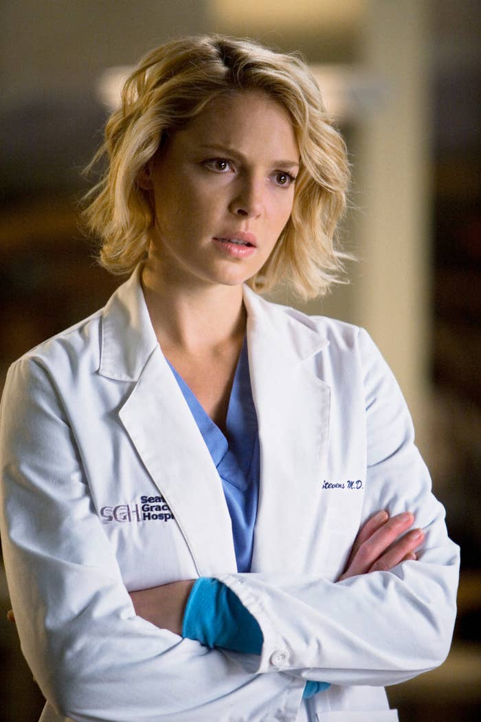 Katherine Heigl as Dr. Izzie Stevens in a hospital scene, wearing a medical coat with folded arms