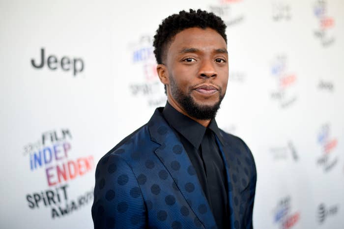 Chadwick Boseman at the Film Independent Spirit Awards, wearing a polka-dot suit with a dark shirt and tie, standing in front of an event backdrop